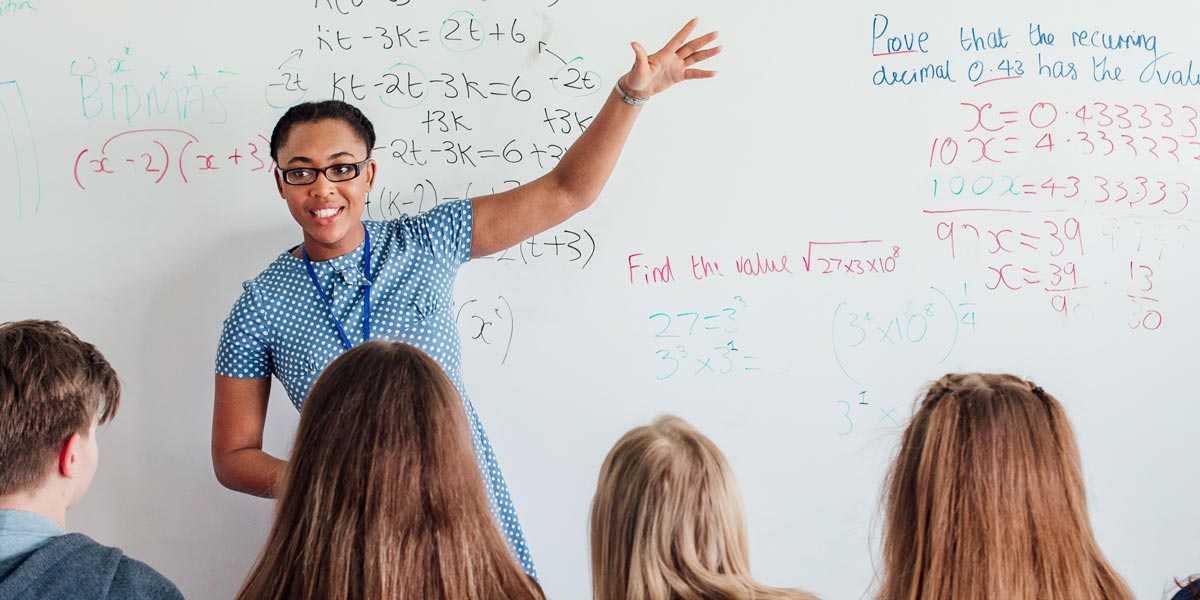 teacher in a classroom in front of a white board