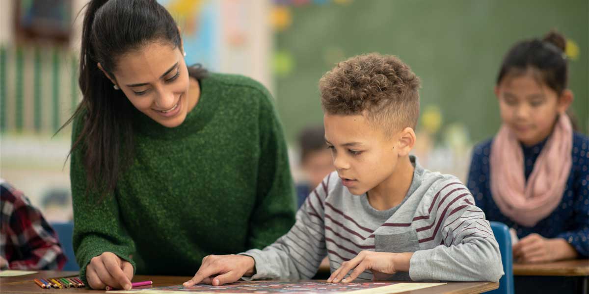 A teacher helping a student at his desk