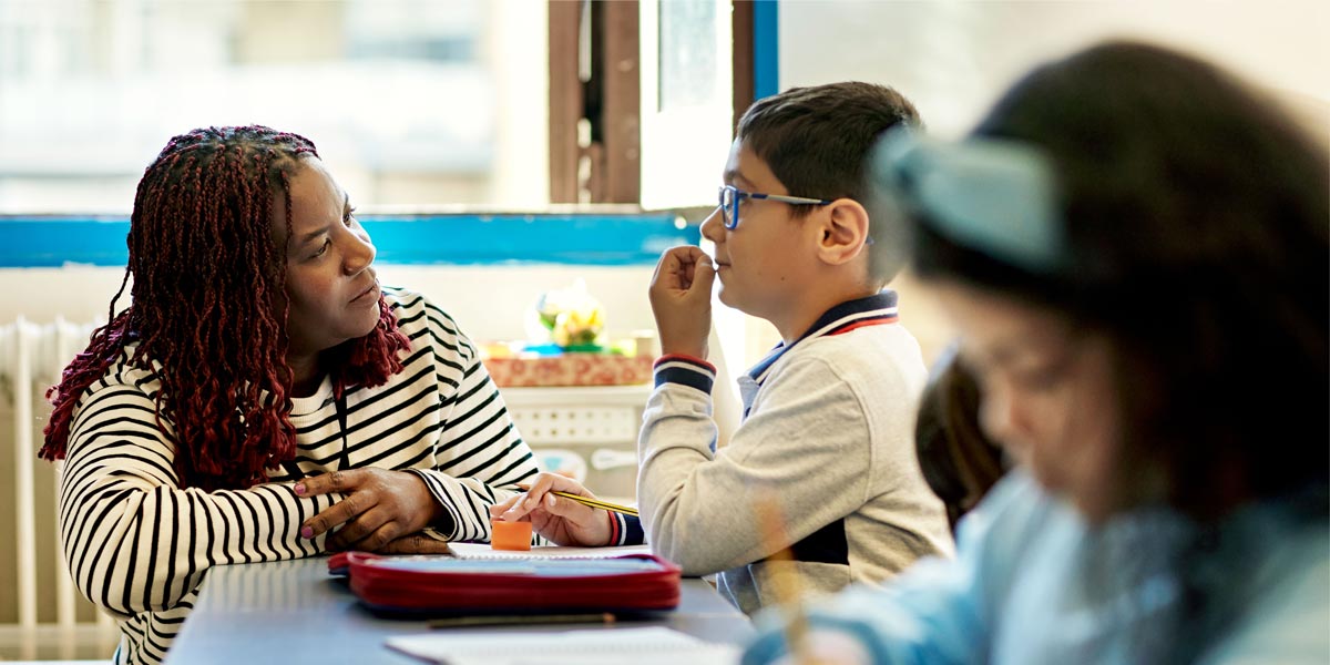 teacher at a students desk in a classroom