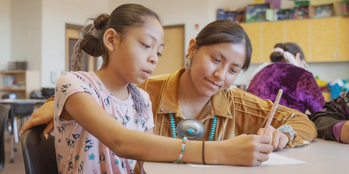 adult tutoring a student in a classroom