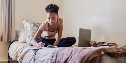 student writing on a bed