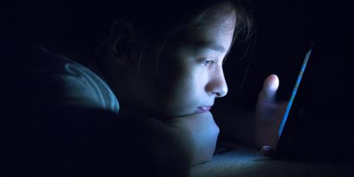 student in the dark looking at a phone
