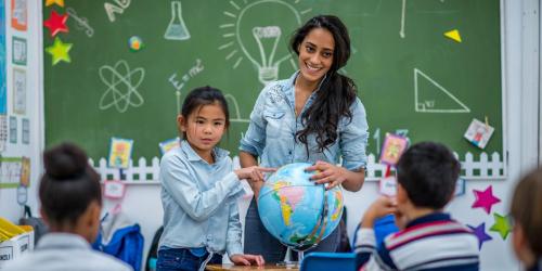 teacher in a classroom with a globe and several students